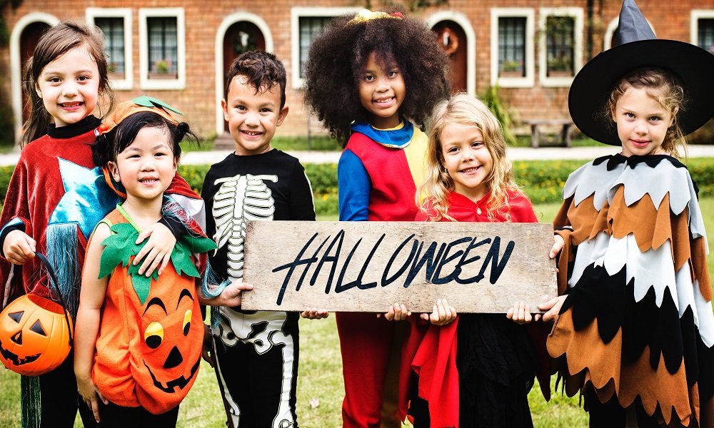 Image of children in fancy dressing holding up Halloween banner