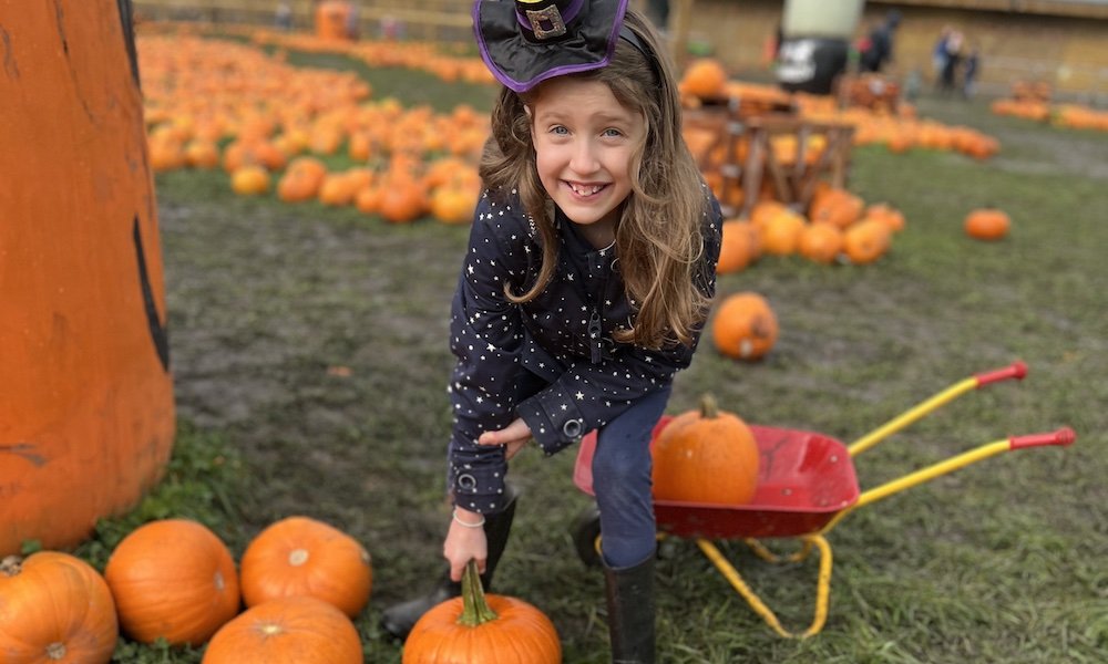 A girl picking a pumpkin October Half Term in Manchester