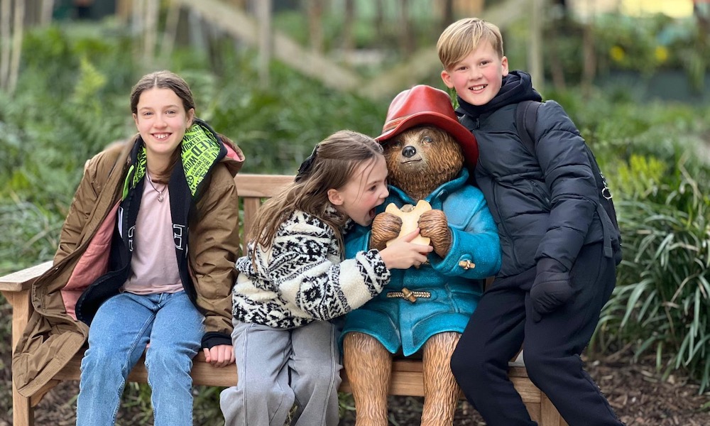 What’s On in Manchester for Kids & Families – Monthly Round-Up three children sat with a paddington bear statue in spinningfields manchester